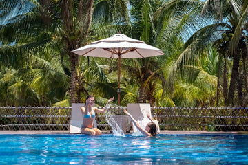 Alizé fan-integrated patio umbrella providing resort-quality shade and active cooling at luxury commercial pool