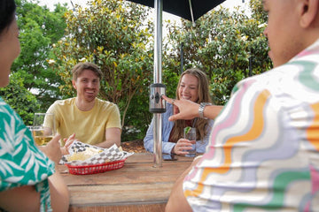 Large group of friends enjoying outdoor entertaining under an Alizé fan patio umbrella in a backyard setting